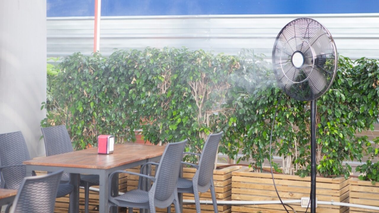 An image of a mist fan emitting a fine water mist, cooling the air on a hot day