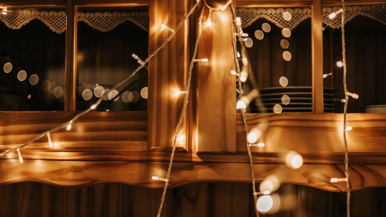 Illuminated string lights draped around a wooden window.