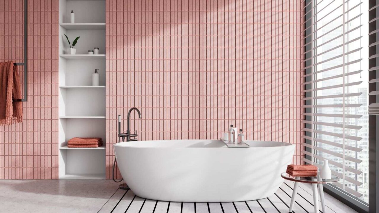 A big white bathtub by the window and a table in a pink bathroom