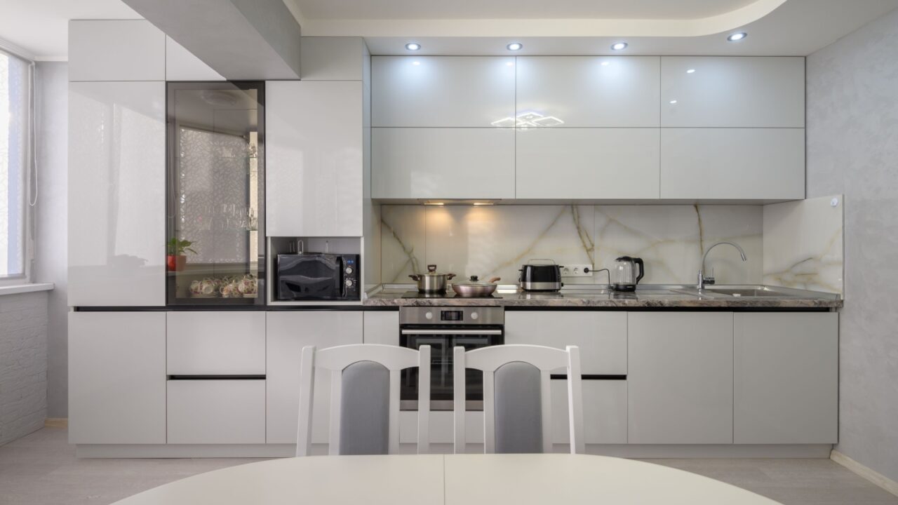 An all white kitchen with white lights and marble countertops