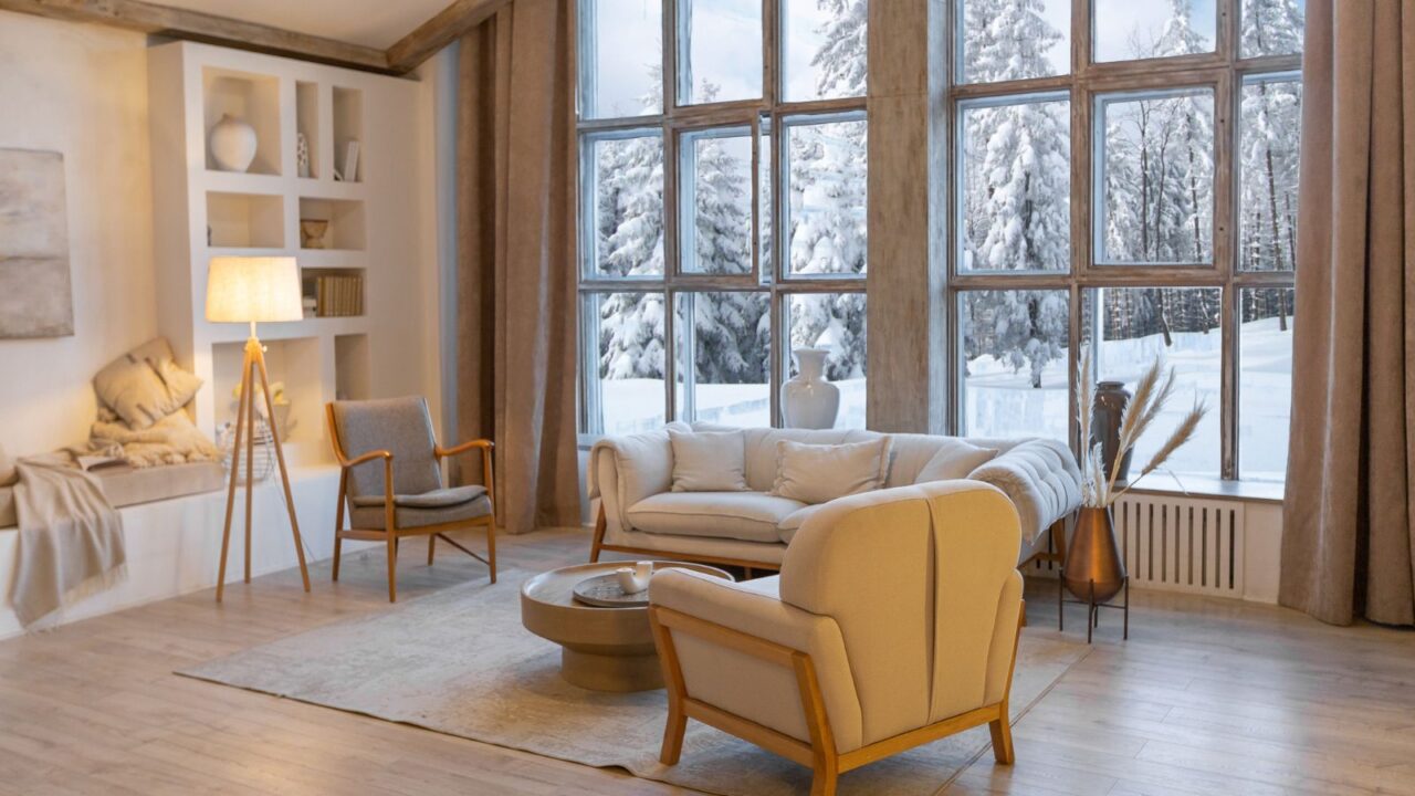 Cozy warm home interior of a chic country chalet with a huge panoramic window overlooking the winter forest. open plan