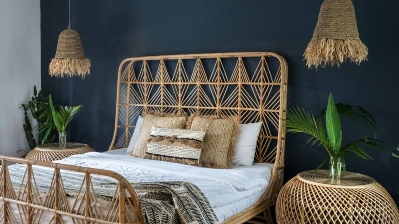 A rattan bed with plants and hangings.