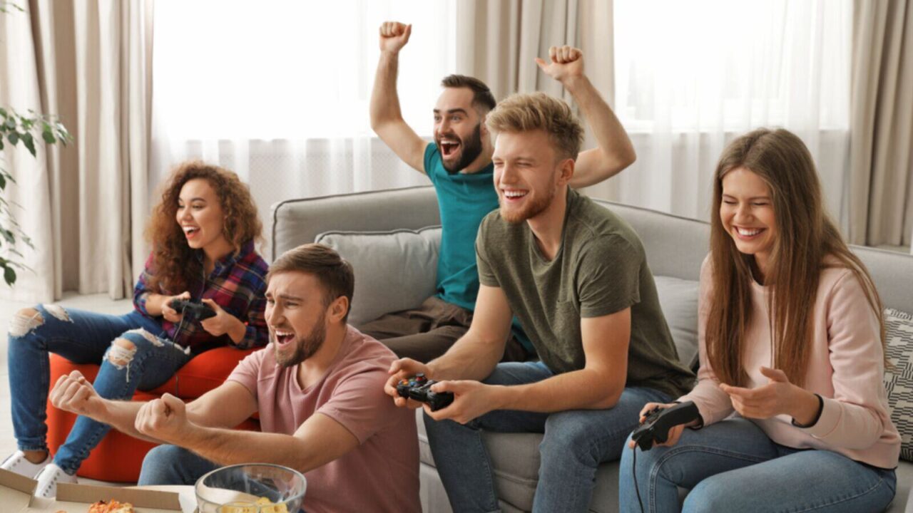 Excited group of friends playing video games at home.