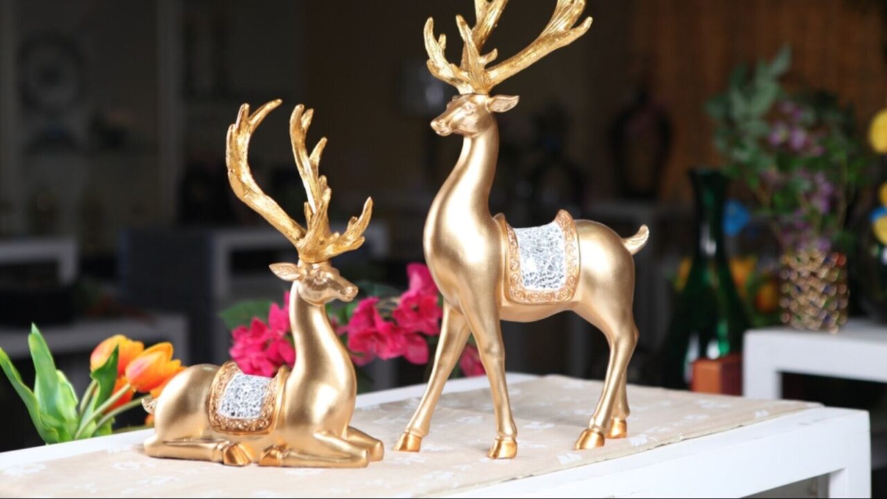 Two golden deer sculptures with horns on a table.