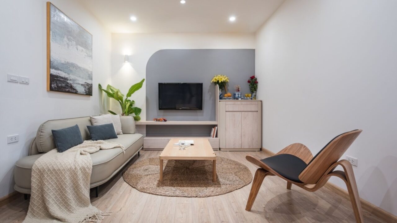 Modern Janpadi living room interior design, wooden furniture, white kitchen, wisbone chairs, hexagon tiles, grey curve wall, warm lighting, neutral color scheme.