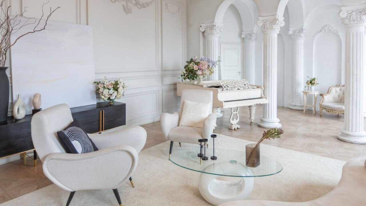 Rich luxurious interior of a cozy room with modern stylish furniture and grand piano, decorated with baroque columns and stucco on the walls.