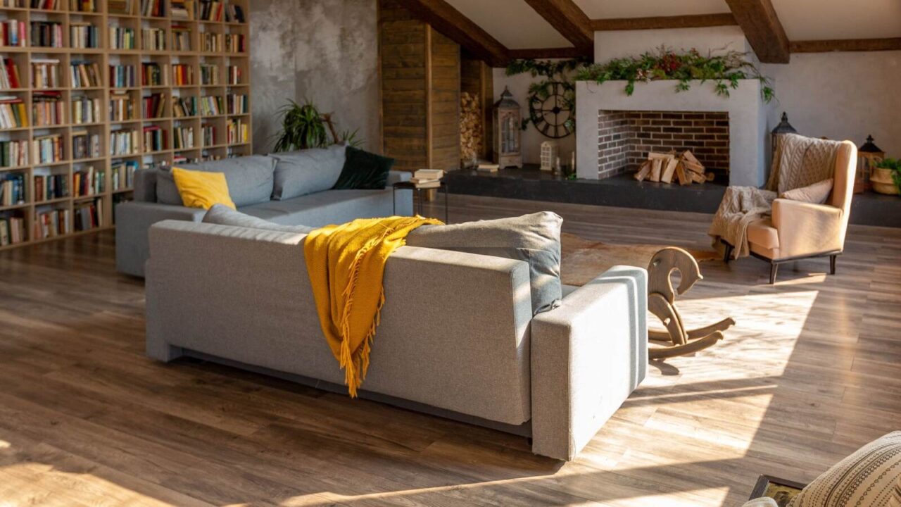 Sunlit loft space decorated with bookshelves and sofas. Fireplace along one wall.