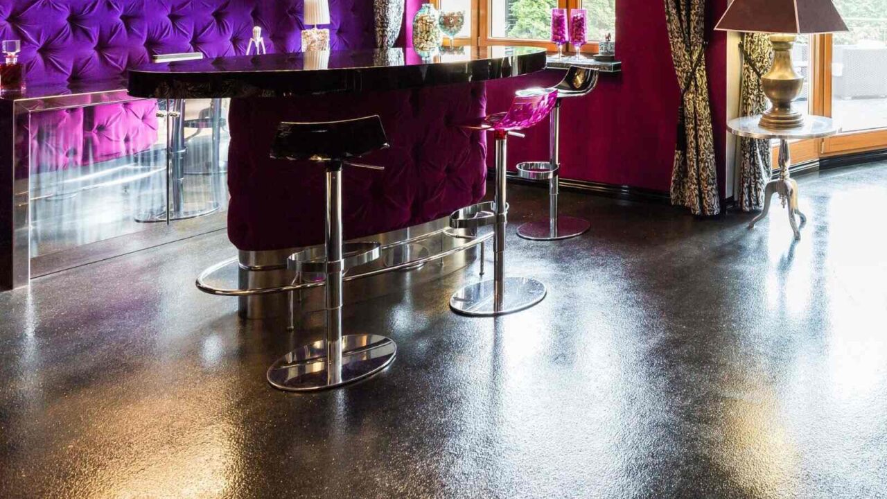 A luxurious home bar setup in a bright living room space. Black bar counter with purple plush backdrop.