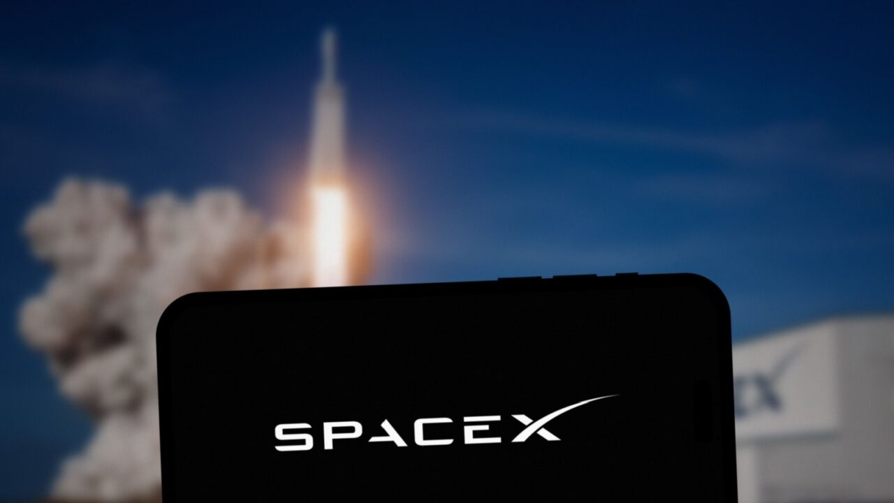 SpaceX logo on a mobile screen. A rocket is launching in the background