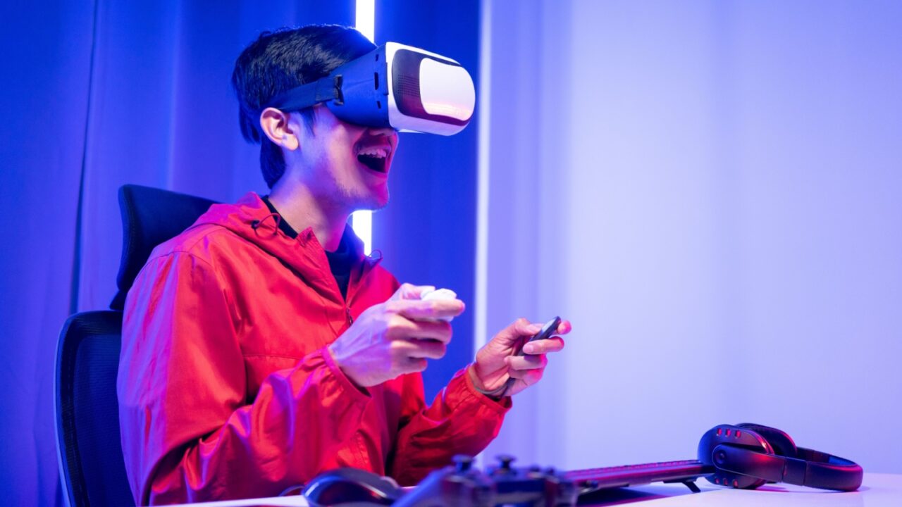 A young guy in red hoodie playing a virtual game wearing VR head gear