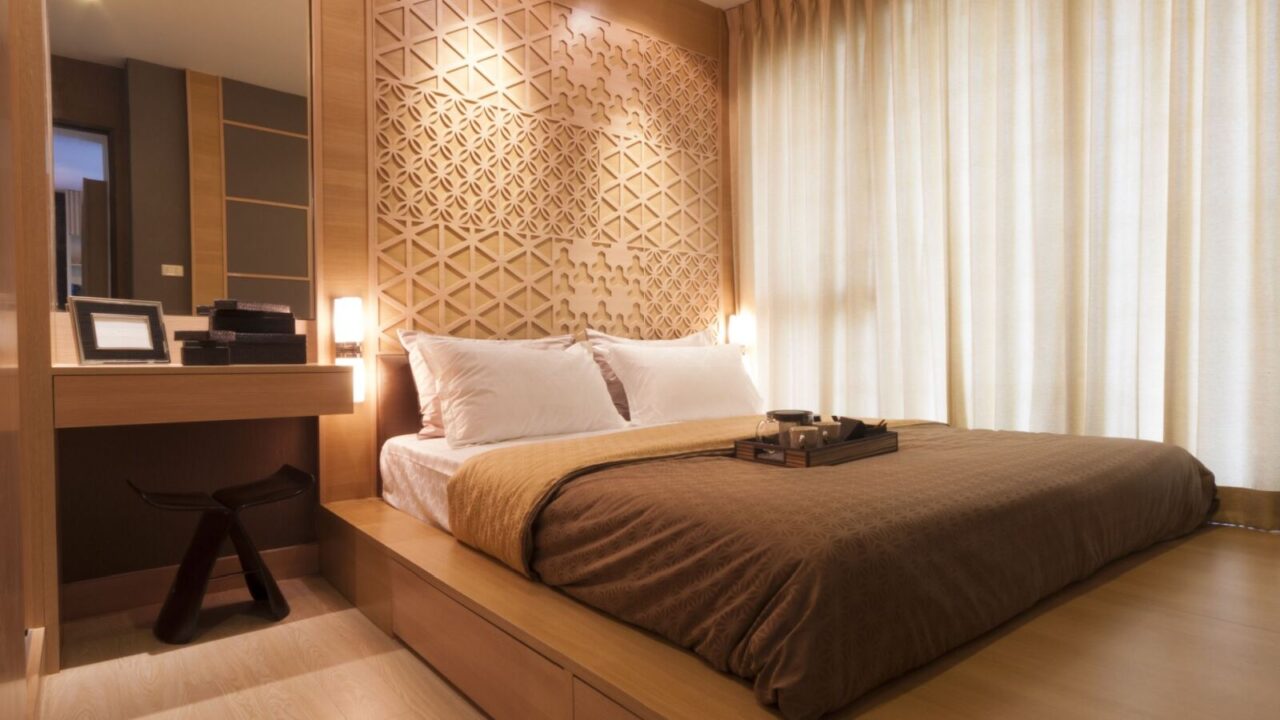 Wooden bedroom with warm lighting and white curtains on windows