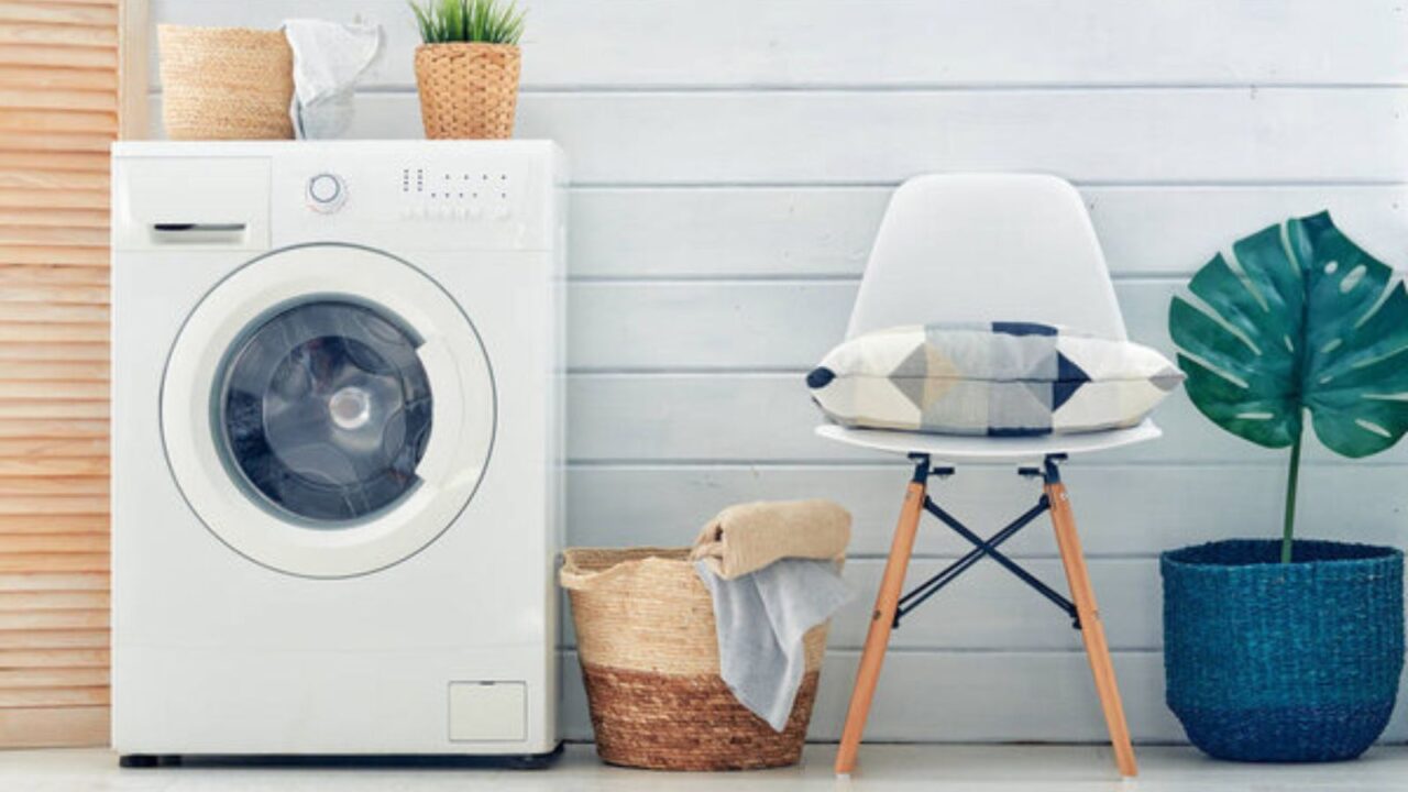 A minimalist laundry space with a front-loading washer, cozy seating, and stylish décor elements for a modern, inviting look.