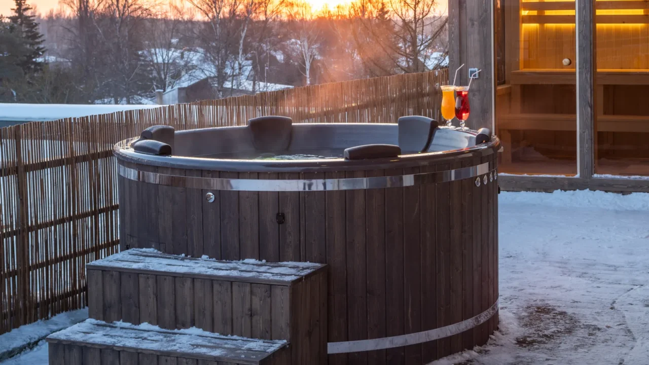 Hot outdoor wooden bath tub on terrace of private house at winter. Luxury cottage. Finnish sauna.