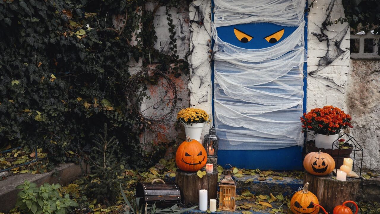 Home or yard entrance decorated for Halloween celebration. Pumpkins, candles, and lanterns are placed on the steps..