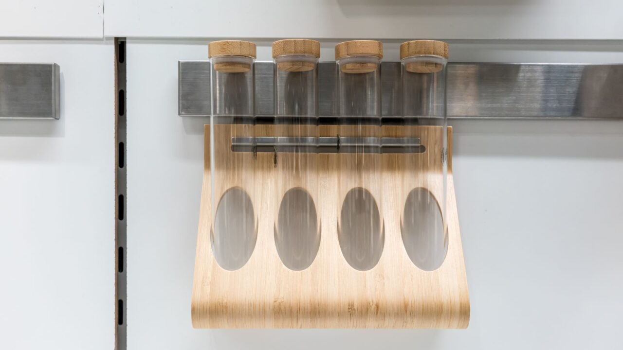 Wall mounted magnetic spices or seasoning tube bottles wooden rack in modern kitchen.