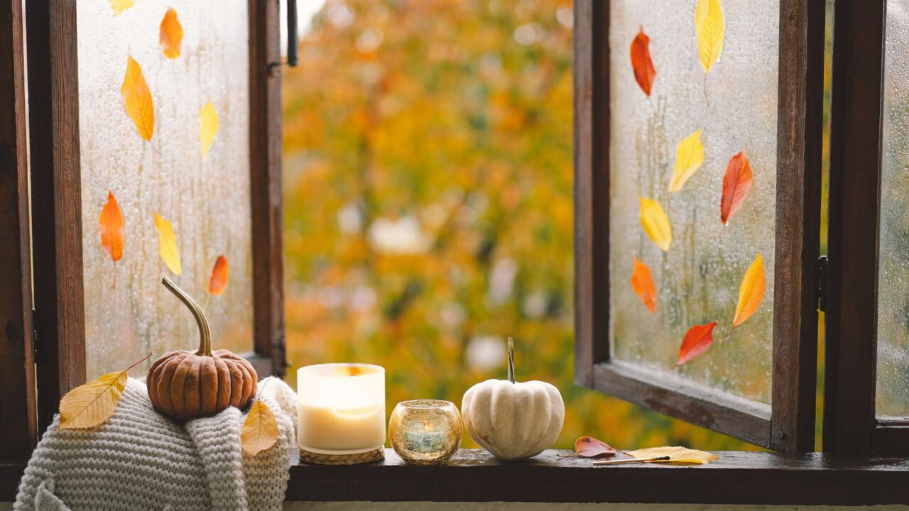 a scented candle and fall decor in a home on a wooden window, Autumn home, cozy fall mood