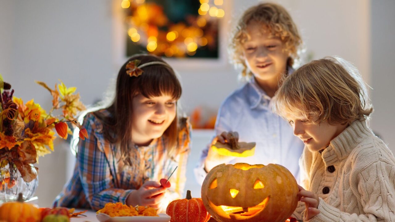 Children carving pumpkin for celebration. Kids decorate the room. Fall decor is all around the room.