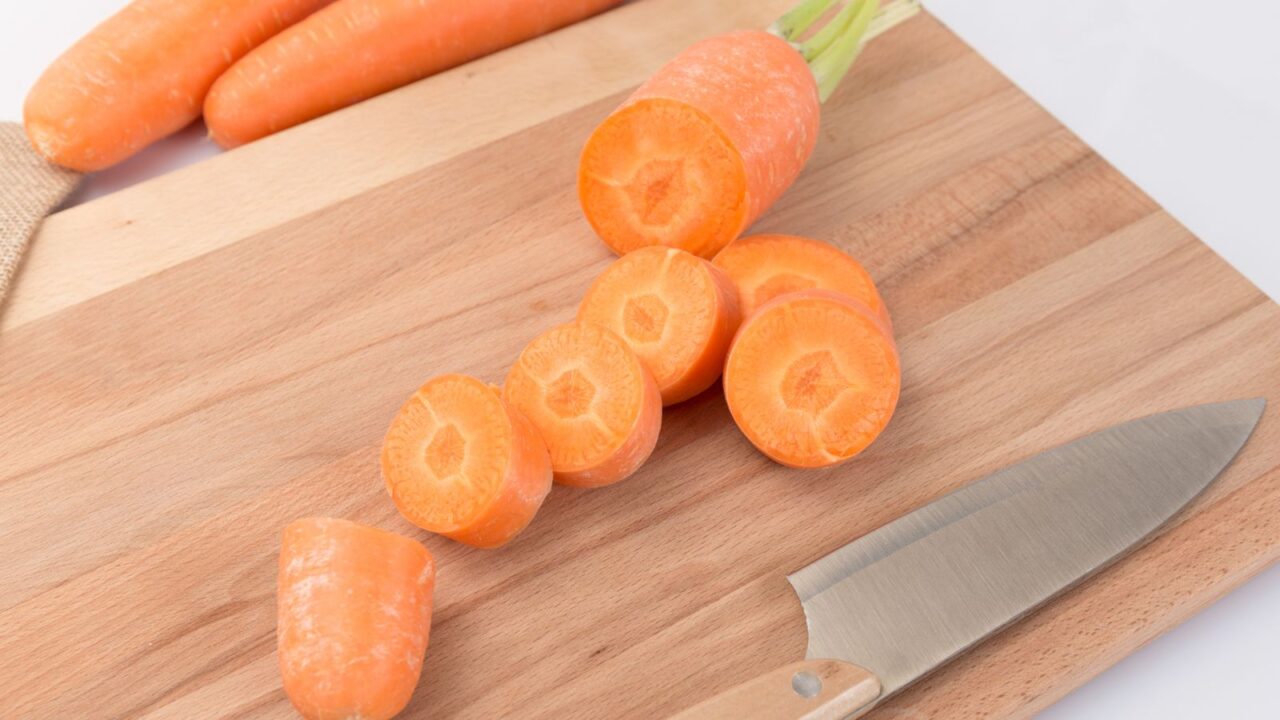 Cutting carrots on a cutting board in kitchen.