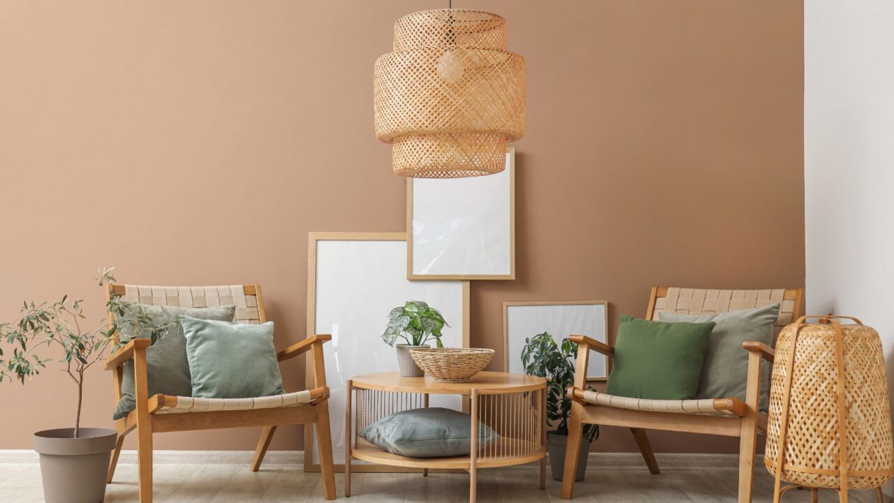 Armchairs with cushions, houseplants, coffee table and wicker lamps near brown wall.