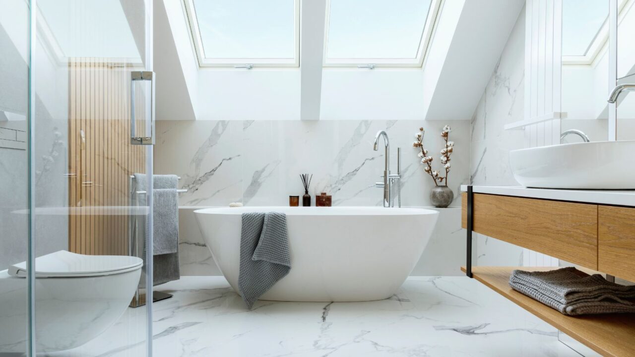 A modern glamorous bathroom interior design with marble panels, bathtub, towels, and other personal bathroom accessories.