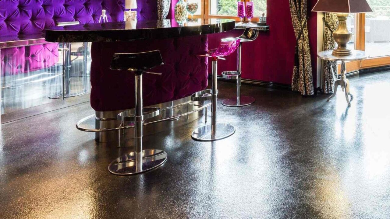 A luxurious home bar setup in a bright living room space. Black bar counter with purple plush backdrop