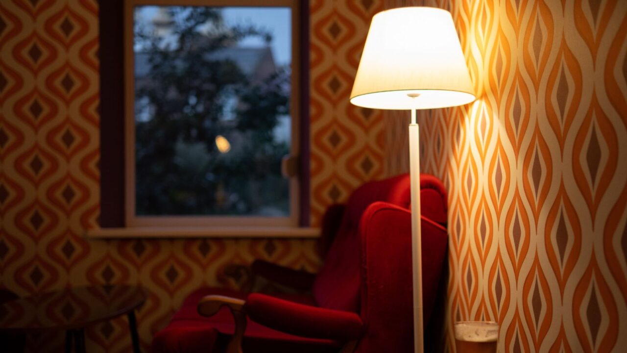 Bold, retro wallpaper in a room with red sofa, lamp and furniture.