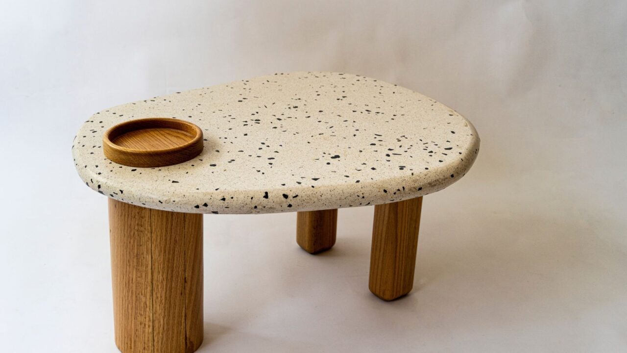 A picture of a table. It has a top of terrazzo and woof base solid wood. Oak wood on white background.