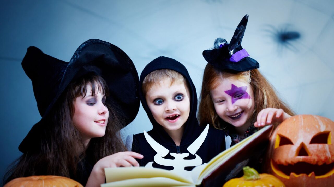 Children in Halloween costumes reading a book