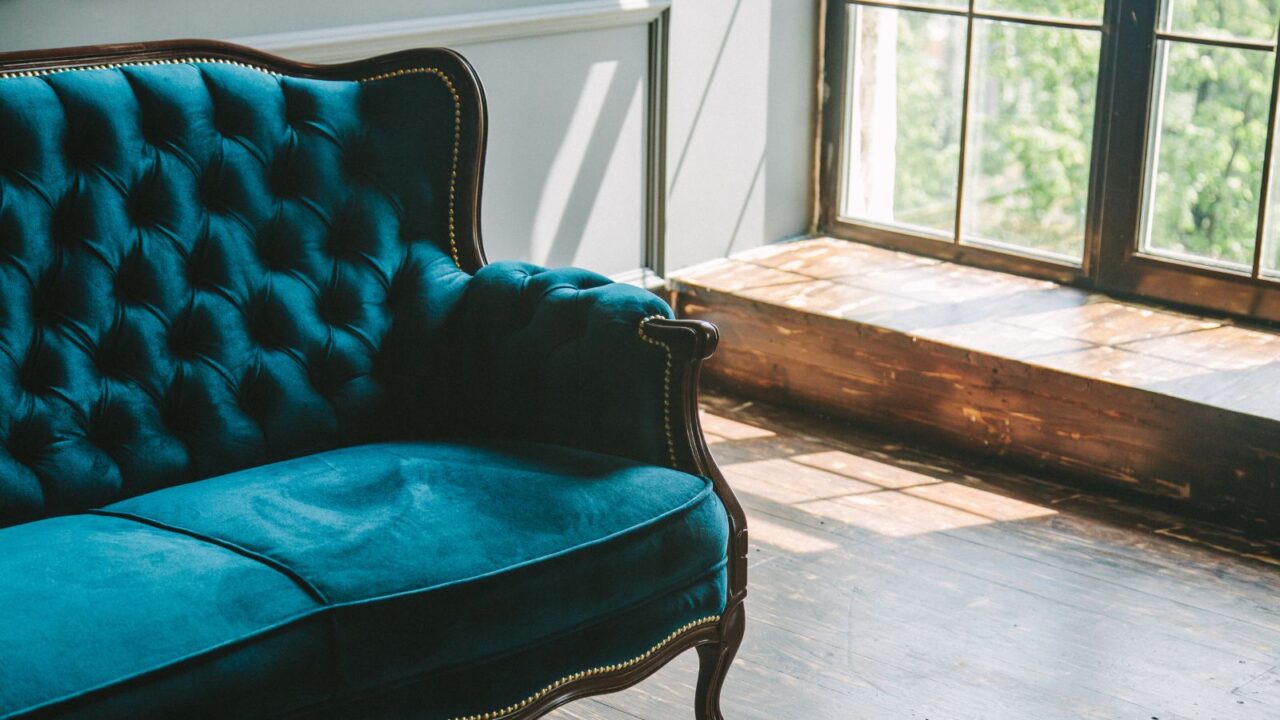 Retro blue velvet sofa near big windows. Classic vintage interior.