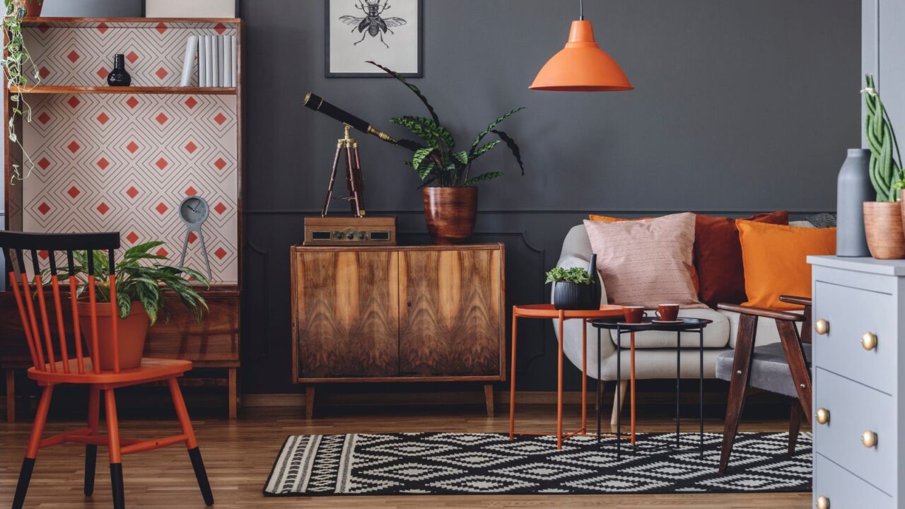 A retro inspired living room with chair, console, vinyl frame, orange lamp, and rug.