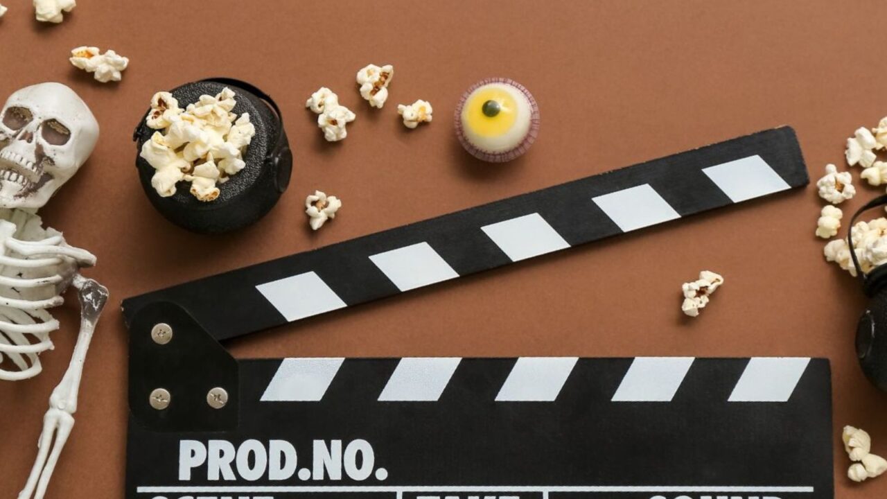 Composition with tasty popcorn, clapperboard, skeleton, ax and candies on brown background. Halloween celebration