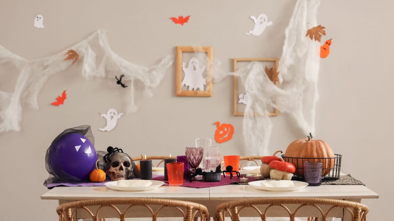 Halloween table setting with spiders, skull, and pumpkins.