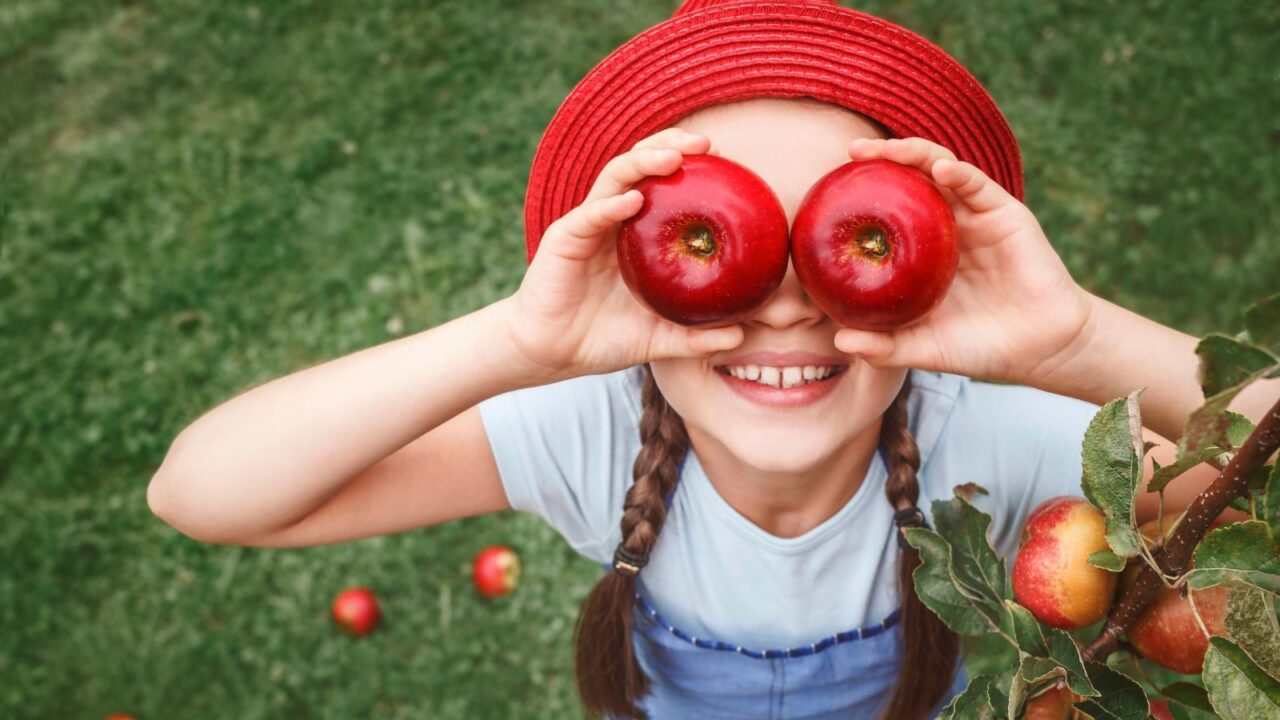 Girl playing and posing with apples. She's enjoying in apple garden orchard.