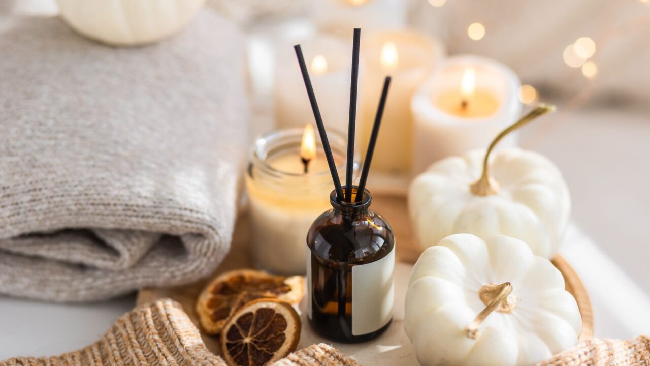 Scented candles and reed diffuser on a wooden tray