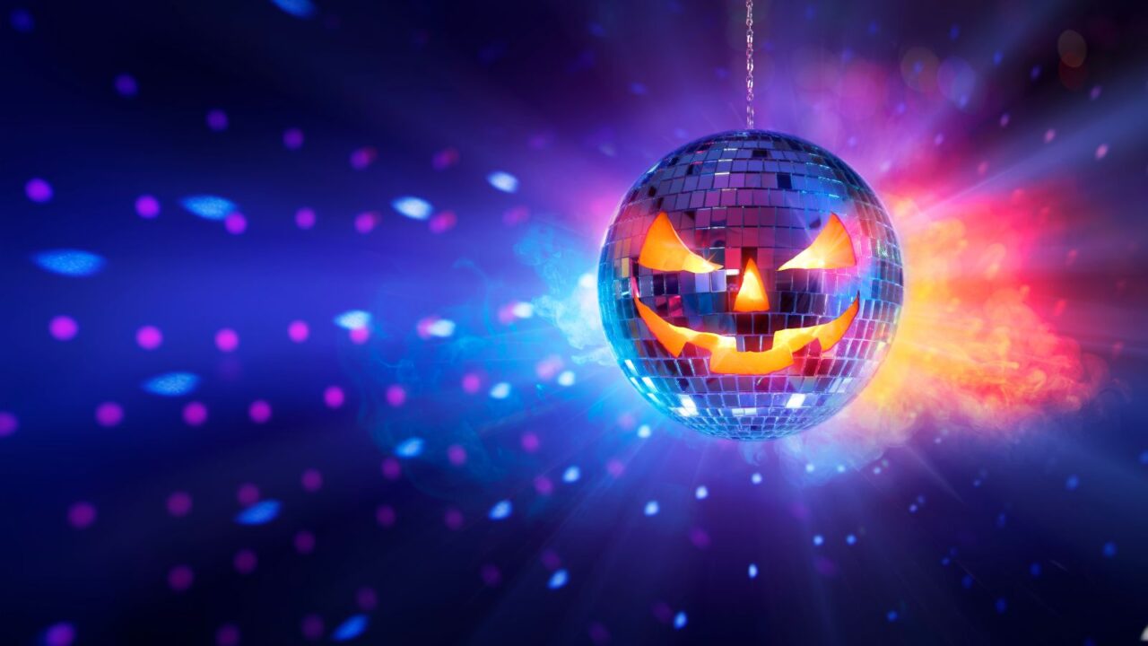 Halloween mirror ball in disco - pumpkins face on sphere in nightclub with smoke and defocused abstract lights.