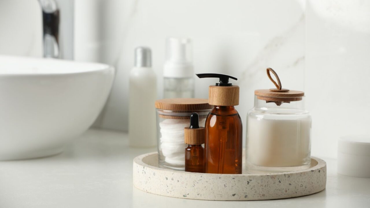 Resin vanity tray with skincare and candle in a bathroom