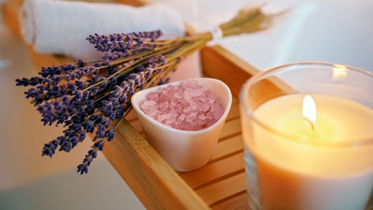 candle, bath salt, lavender, and towel in a wooden tray