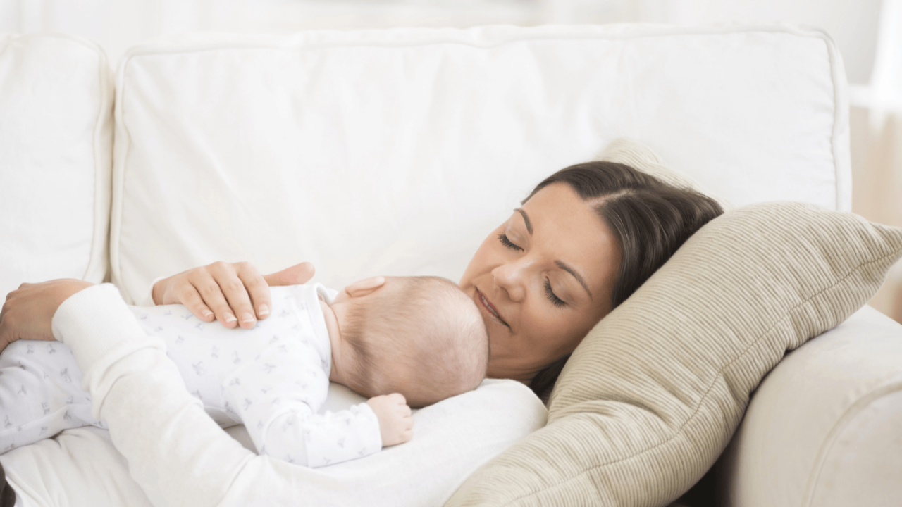 Woman with a baby lying on a couch