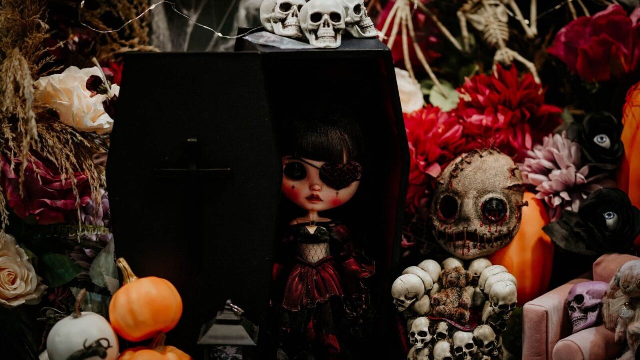 Creepy Halloween doll and voodoo doll with skulls and pumpkins around them