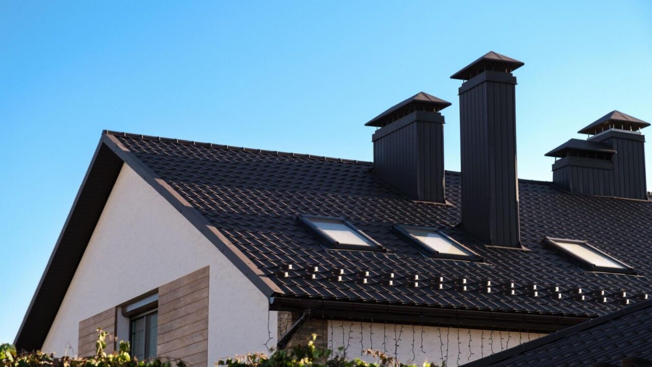 Tiled house roof with two chimneys and skylights