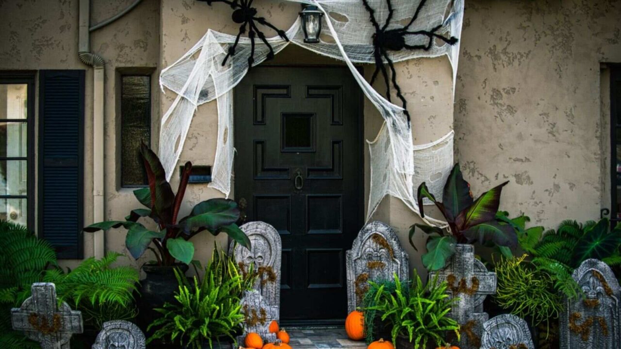 Halloween decor on porch with spiders, spiderweb, pumpkins and tombstones