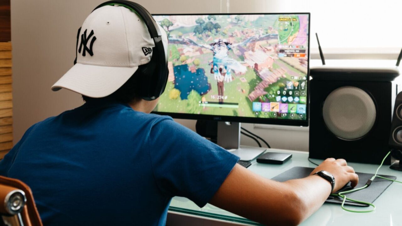 Teenager playing Fortnite video game on PC.