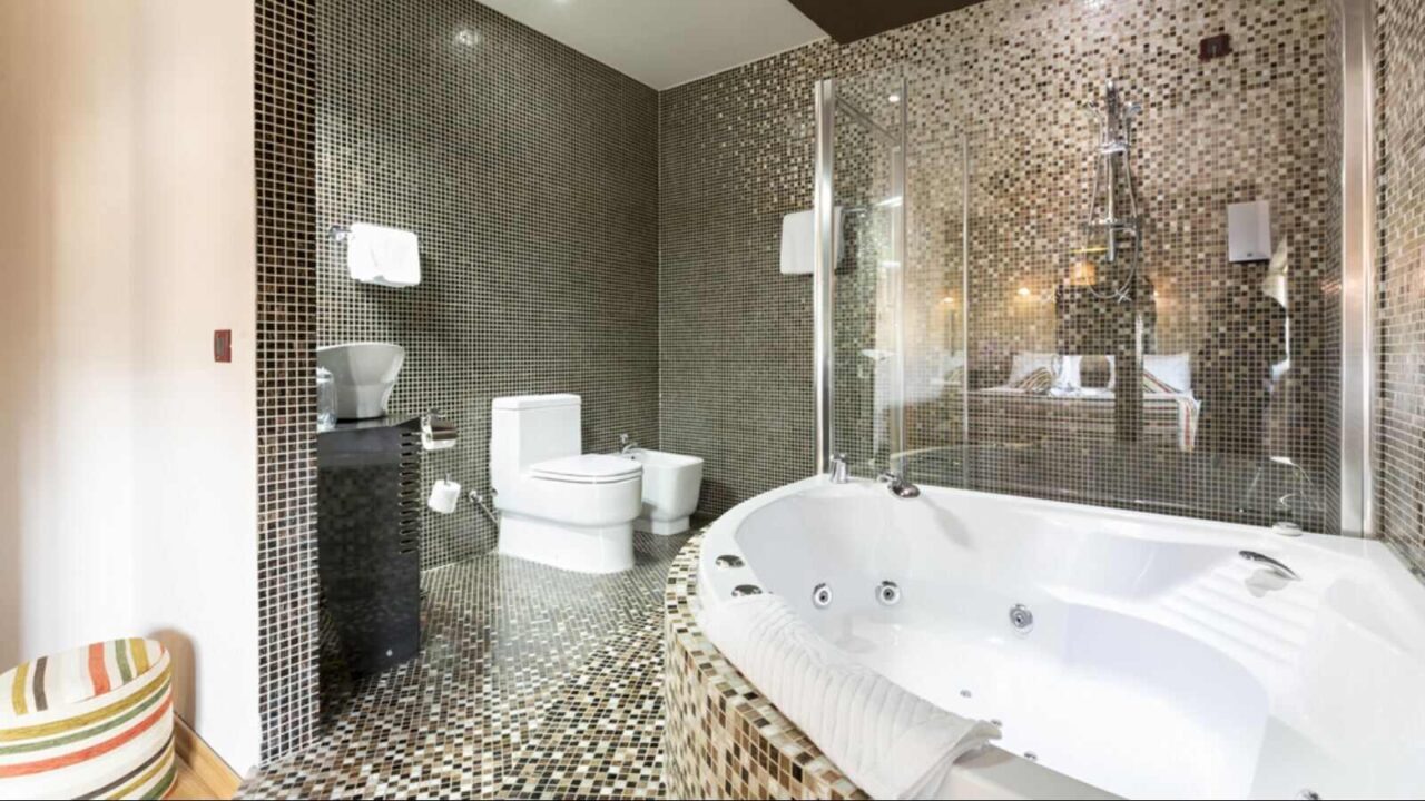 Modern bathroom with jacuzzi tub and geometric floor and wall tiles.