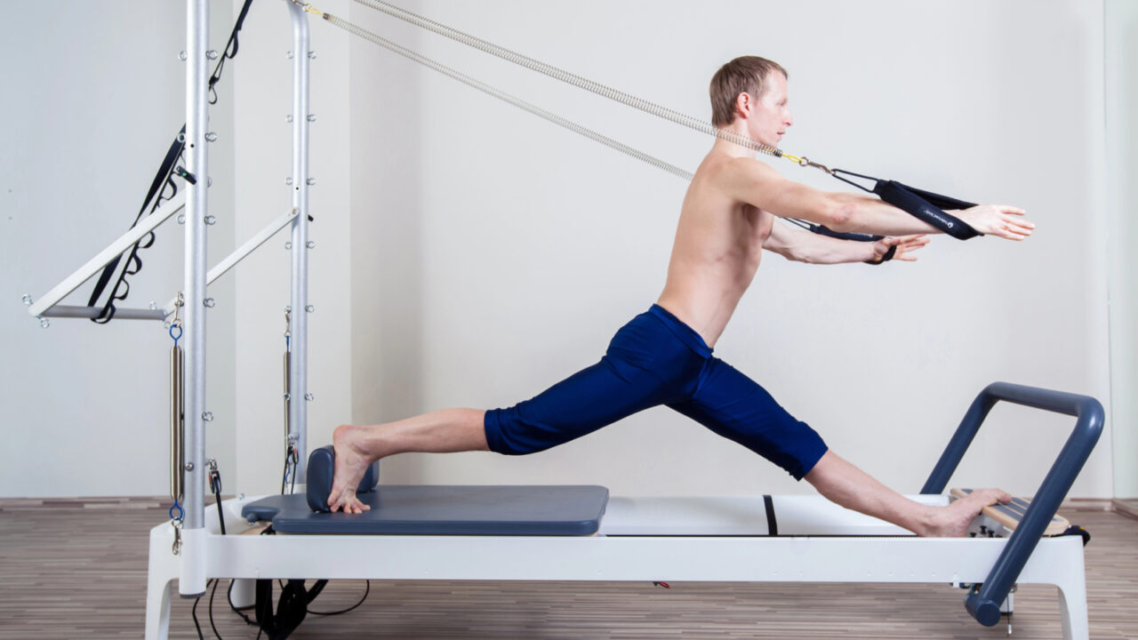 Pilates reformer workout exercises man at gym indoor