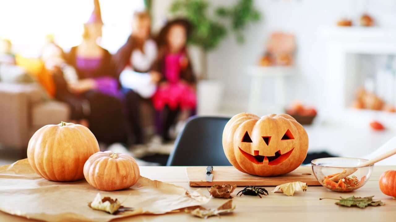 Messy kitchen counter with pumpkins, fallen leaves, and a fake spider