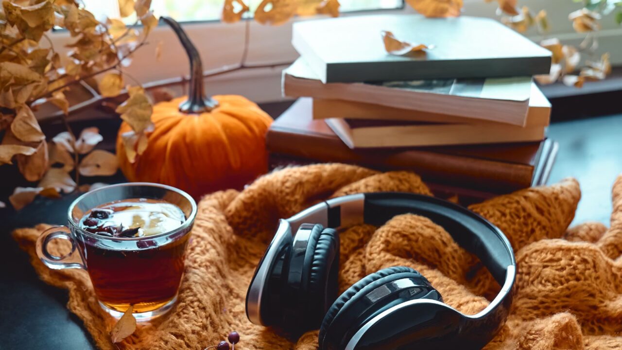 Headphones, books, and tea are on the table with fall decor