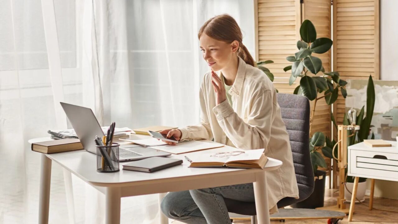 A girl working on her work desk, near the window at home.