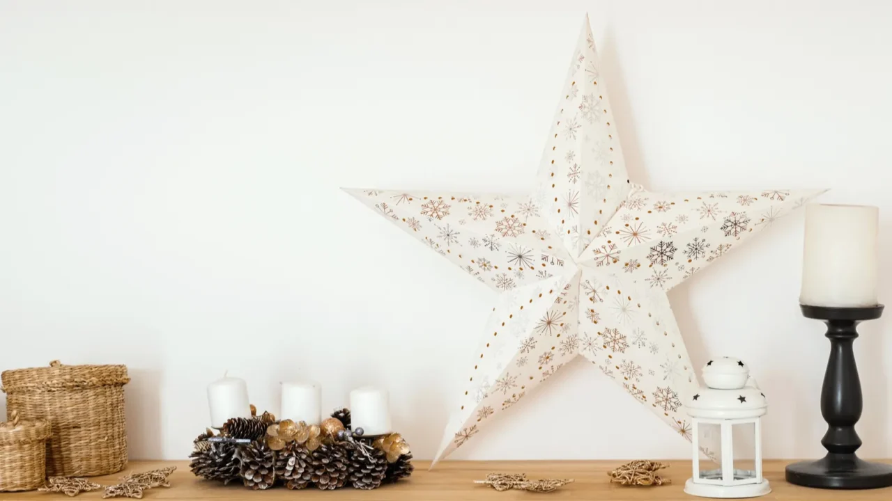 A beautifully arranged wooden shelf features a large star decoration, rustic candles, and natural elements like pinecones and woven baskets, creating a warm and inviting atmosphere.