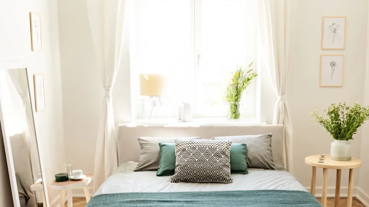 A big bed dressed in earth colors linen with cushions and a blanket standing in an eco friendly bedroom interior. Real photo.