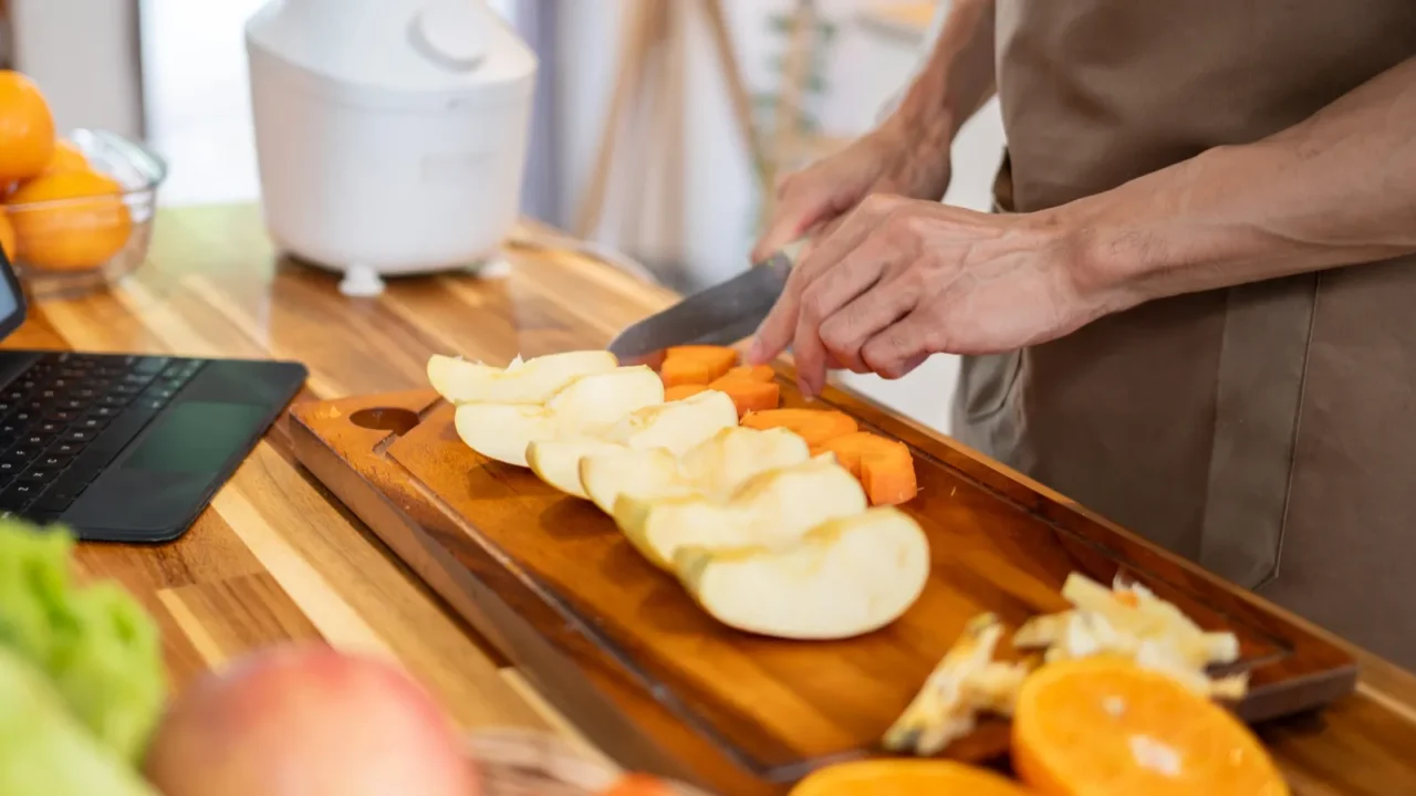 A close-up image of a man preparing food at the kitchen table while checking a recipe on his digital tablet. domestic life, lifestyles, healthy food